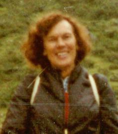 Porträt einer lächelnden Frau mit vollen Haaren im Freien.