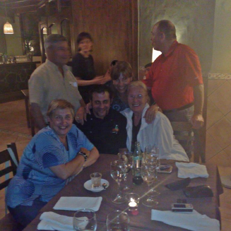 Eine Gruppe von Menschen sitzt zusammen an einem gedeckten Tisch in einem Restaurant und lächelt.