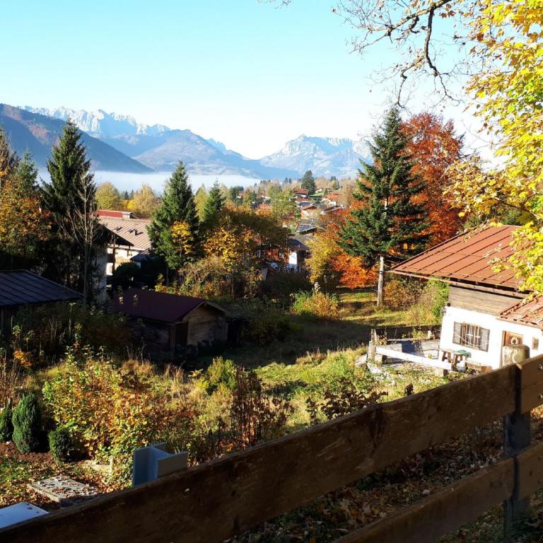Herbstliche Landschaft mit Häusern, Bäumen und majestätischem Bergpanorama