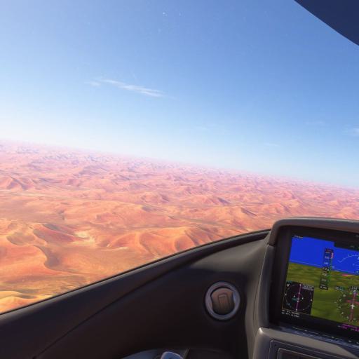 Flugansicht über eine ausgedehnte, rötliche Wüstenlandschaft, aufgenommen aus der Perspektive eines Cockpits.