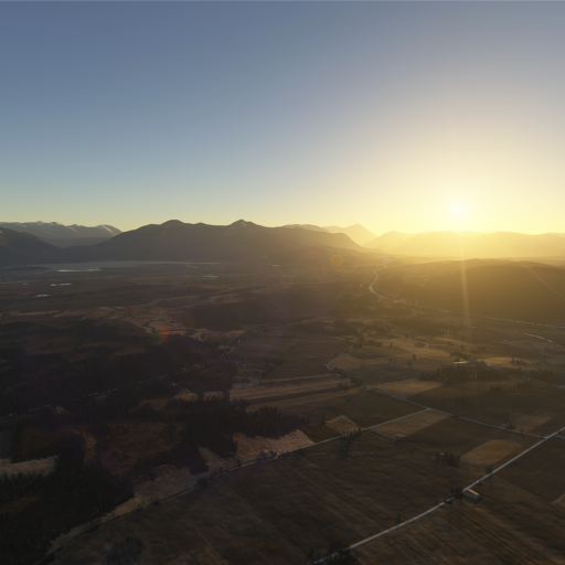 Panoramaaufnahme einer weiten Landschaft mit Feldern, Waldstücken und Bergen bei Sonnenaufgang.